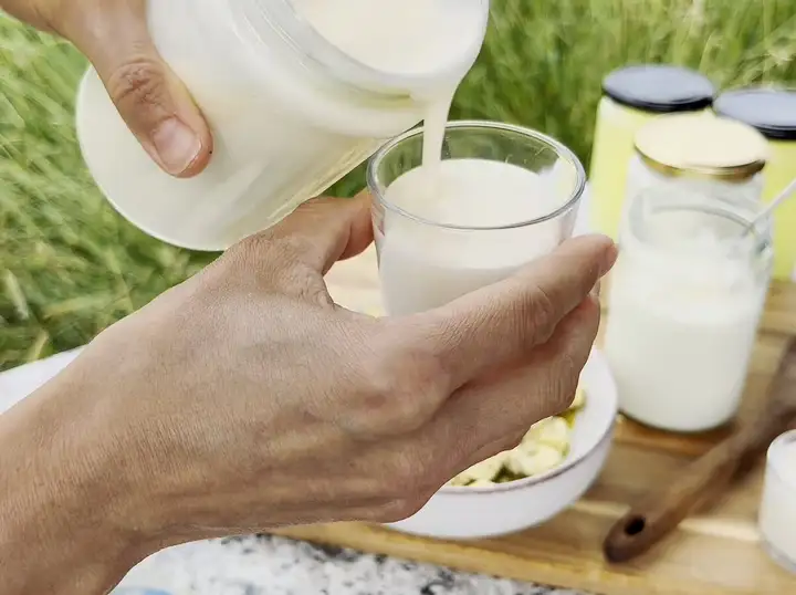 Eiskalter, schaumiger Ayran in einem Tonkrug an einem Grilltisch